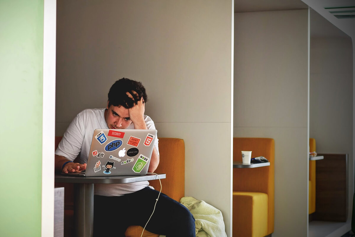 a person sitting in front of a laptop with a frustrated look